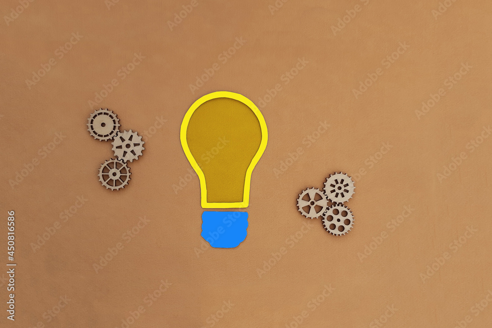 Electric light bulb, wooden gears on a beige background. The mechanism of creativity, solutions, ideas.