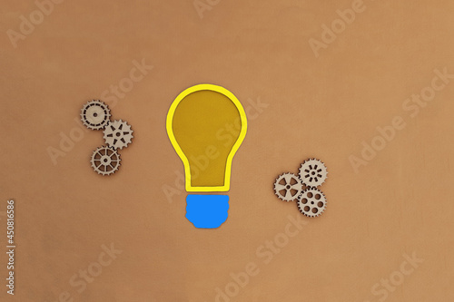 Obraz na płótnie Electric light bulb, wooden gears on a beige background. The mechanism of creativity, solutions, ideas. w salonie