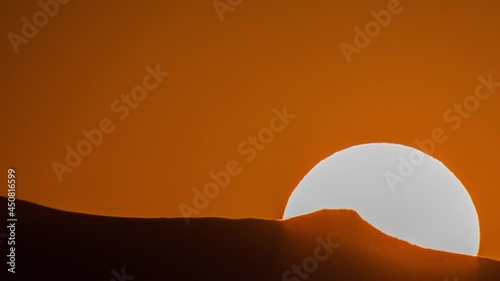 The sun is setting behind the mountains. 4K Timelapse