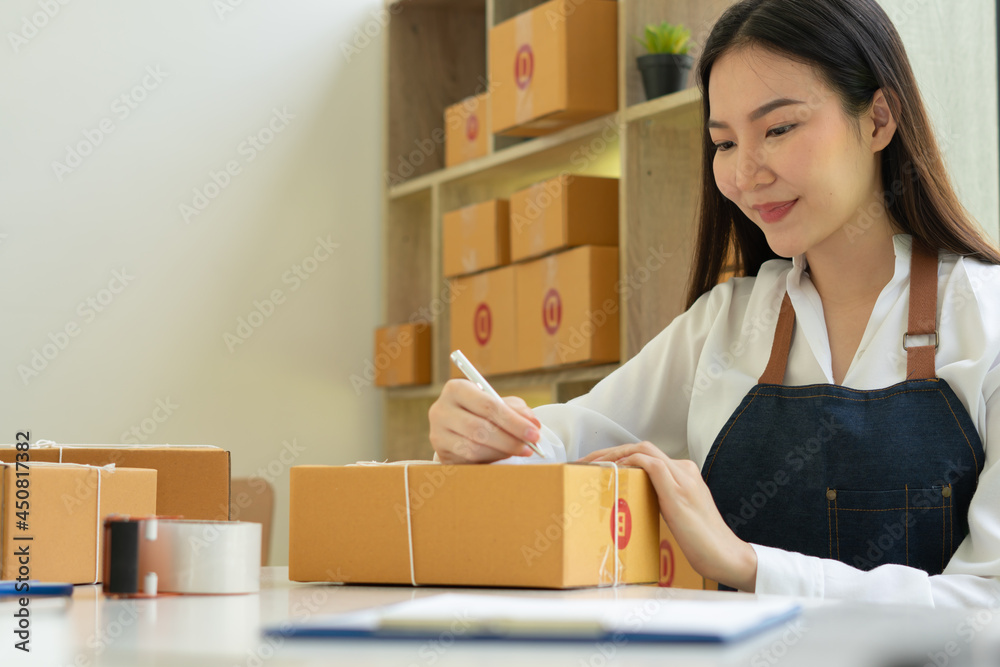 Startup small business entrepreneur SME, young asian woman working with laptop computer and delivery packaging box, online market packing, SME e-commerce seller concept. Startup small business entrepreneur SME, young asian woman working with laptop computer and delivery packaging box, online market packing, SME e-commerce seller concept.