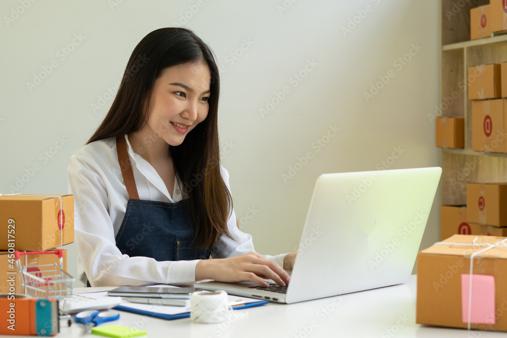 Startup small business entrepreneur SME, young asian woman working with laptop computer and delivery packaging box, online market packing, SME e-commerce seller concept. Startup small business entrepreneur SME, young asian woman working with laptop computer and delivery packaging box, online market packing, SME e-commerce seller concept.