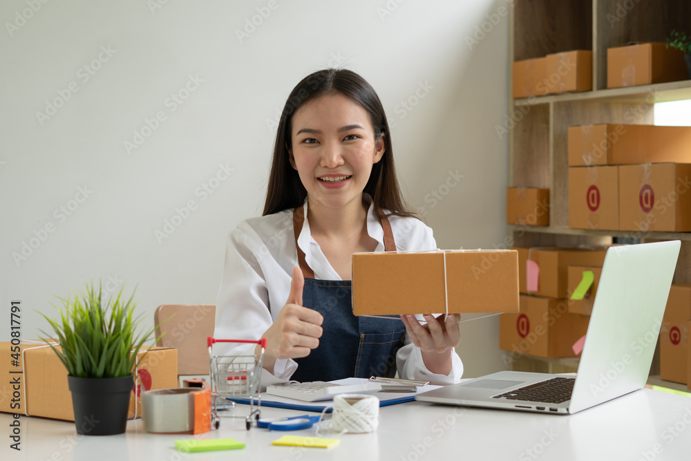 Startup small business entrepreneur SME, young asian woman working with laptop computer and delivery packaging box, online market packing, SME e-commerce seller concept. Startup small business entrepreneur SME, young asian woman working with laptop computer and delivery packaging box, online market packing, SME e-commerce seller concept.