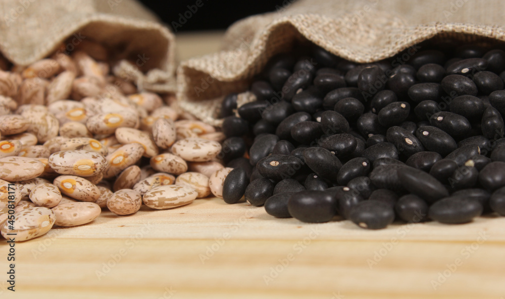Fototapeta premium Dried Pinto Beans and Black Beans in Burlap Bag on Wooden Background
