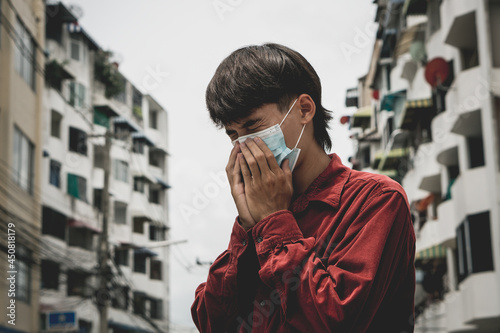 Young asia man can't breathe because wearing the respiratory protection mask against air pollution and dust particles exceed the safety limits.environmental, ecology concept.headache.