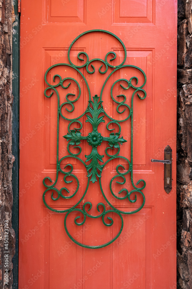 Traditional and decorative ornament made of iron placed on a red wooden door. Traditional and decorative ornament made of iron placed on a red wooden door.