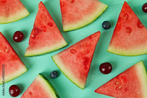 Flat lay with watermelon slices and berries on mint background