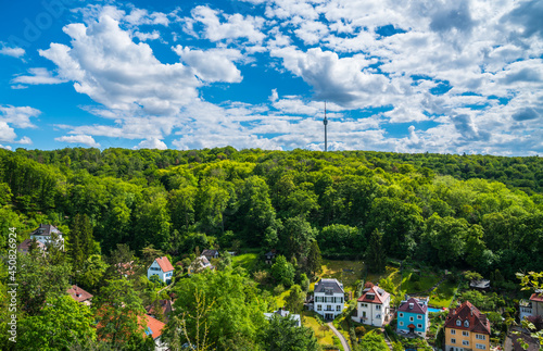 Germany, Stuttgart television tower building surrounded by green trees of forest on sunny day, aerial panorama drone view above the tree tops and houses photo