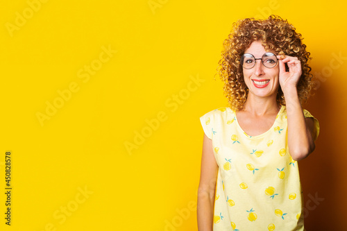smiling young woman in round transparent glasses on a yellow background