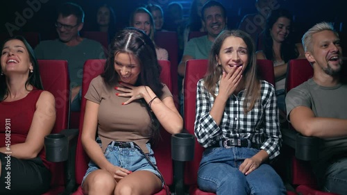 Two female friends laughing having positive emotion at comedian movie sitting on armchair row