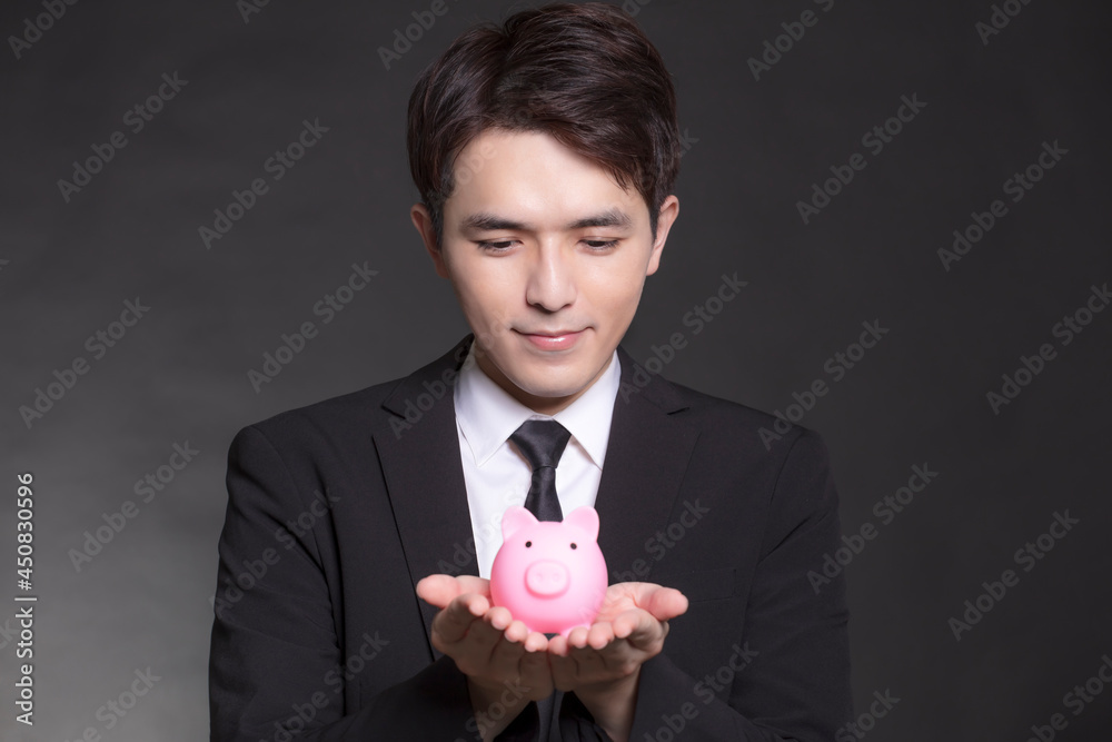 Business man in black suit and holding pink piggy bank Business man in black suit and holding pink piggy bank