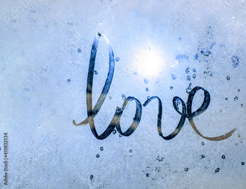 winter blue window glass with sun, inscription love on frozen glass, Valentine's Day card with copy space