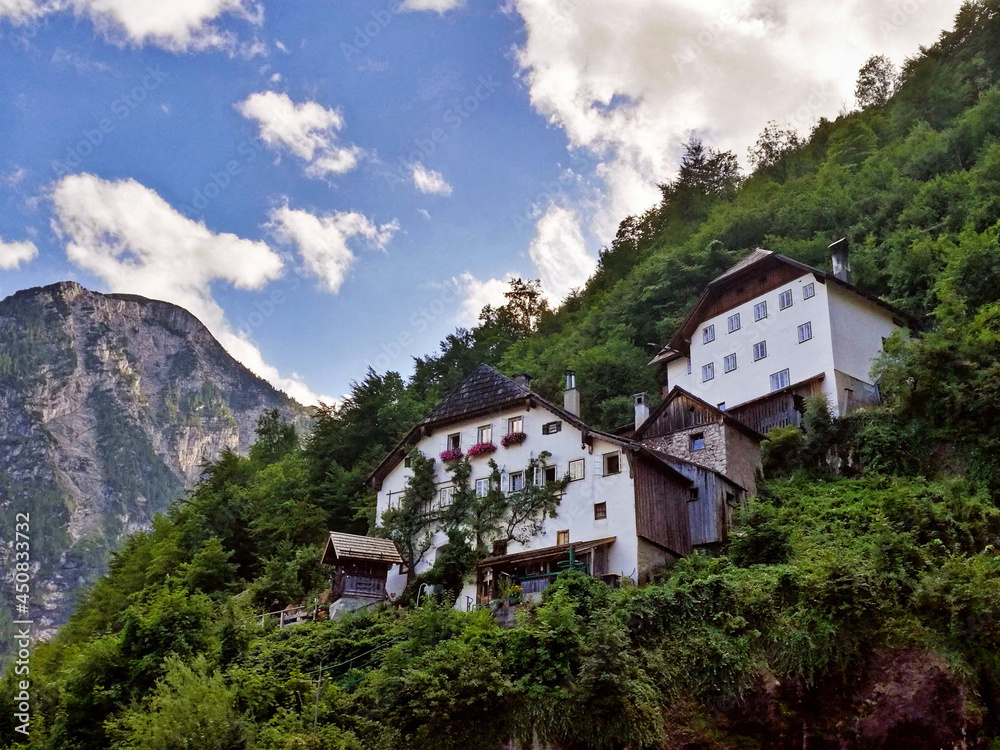 Two big white houses in the middle of a green mountain in Hallstatt, Austria.