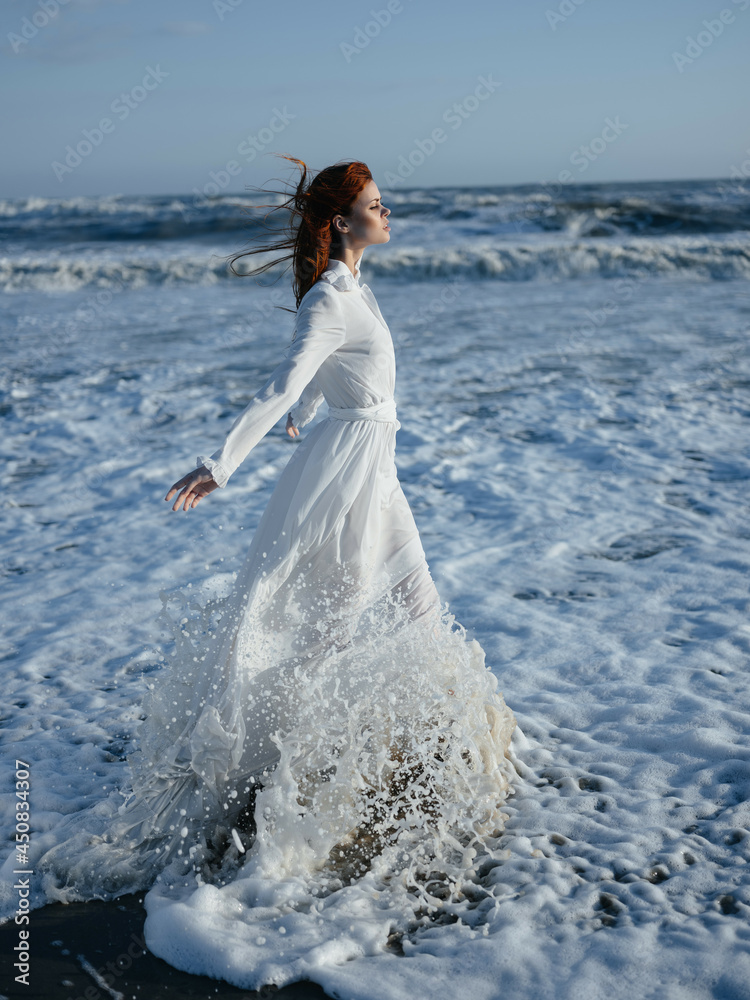 Woman in white dress walking along the coast of the ocean Freedom fashion