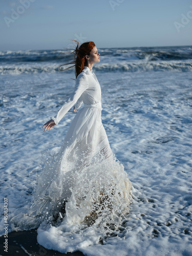 Woman in white dress walking along the coast of the ocean Freedom fashion