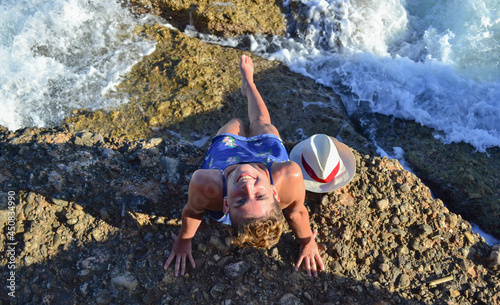 Beautiful young woman in a dress sitting by the sea in Spain.