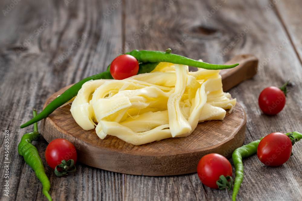 Chechil cheese or string cheese on wood floor. Cheese on serving board Chechil cheese or string cheese on wood floor. Cheese on serving board