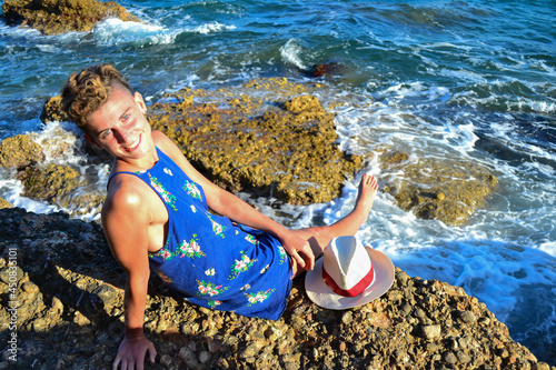 Beautiful young woman in a dress sitting by the sea in Spain.