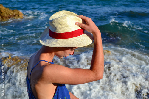 Beautiful young woman in a dress sitting by the sea in Spain.