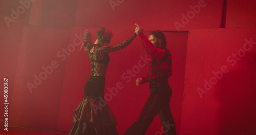 4K Beautiful couple dancing latin dance . Professional dancers dancing flamenco, rumba or salsa on red background. Pair in spanish dress performs dance movement. Shot ARRI ALEXA Camera in Slow Motion 