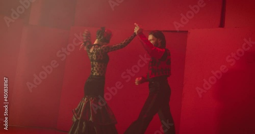 4K Beautiful couple dancing latin dance . Professional dancers dancing flamenco, rumba or salsa on red background. Pair in spanish dress performs dance movement. Shot ARRI ALEXA Camera in Slow Motion  photo