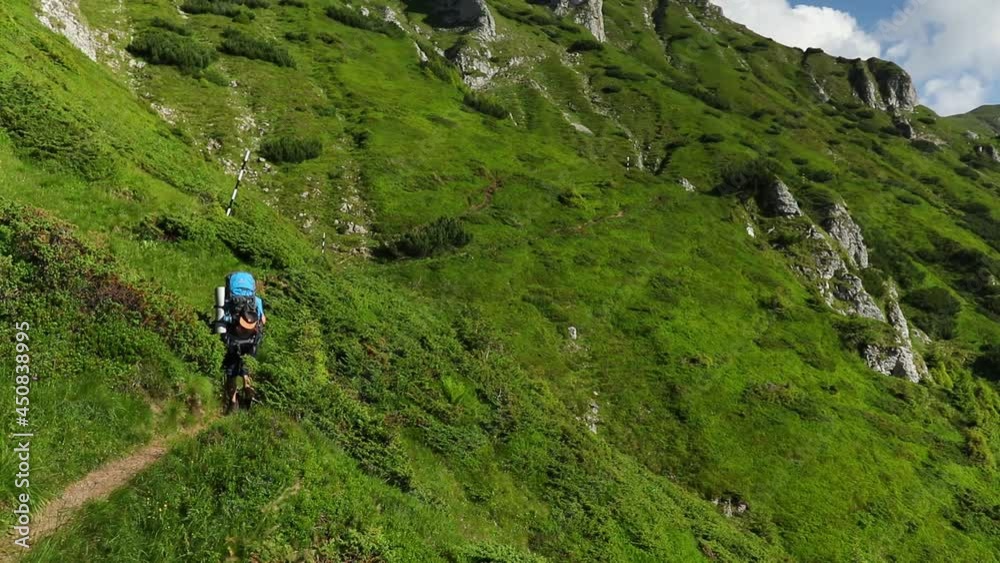 Lonely hiker with a backpack walking on high mountain in summer Lonely hiker with a backpack walking on high mountain in summer
