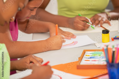 Close-up view of a girl drawing with colored pencils in art class