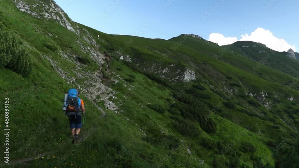 Lonely hiker with a backpack walking on high mountain in summer Lonely hiker with a backpack walking on high mountain in summer