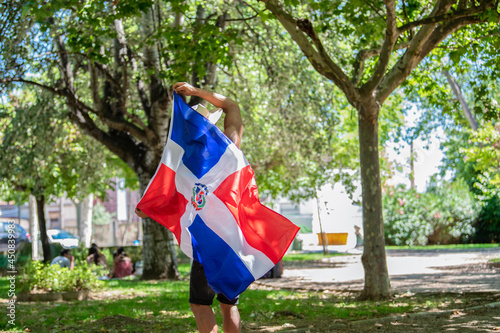 Latino man holding a Dominican Republic flag outdoors