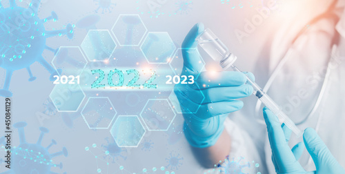 2022 health insurance concept. Doctor or scientist with stethoscope in hand with syringe vaccine showing health insurance related icons on virtual screen. 