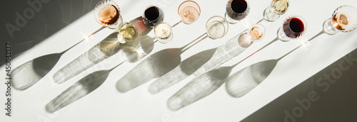 Fotografi Glasses of wine on white table with shades, top view, copy space