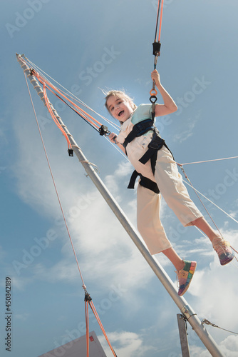 Jumping rubber band in an amusement park. Girl jumping on a trampoline ride with rubber belay ropes