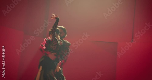 4K Beautiful couple dancing latin dance . Professional dancers dancing flamenco, rumba or salsa on red background. Pair in spanish dress performs dance movement. Shot ARRI ALEXA Camera in Slow Motion 