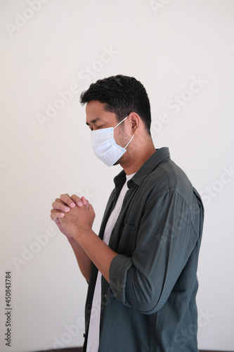 Side view of Asian man wearing protective mask when praying photo
