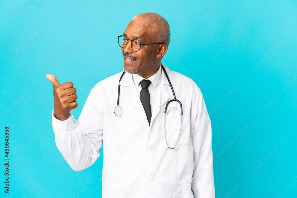 Senior doctor man isolated on blue background pointing to the side to present a product Senior doctor man isolated on blue background pointing to the side to present a product