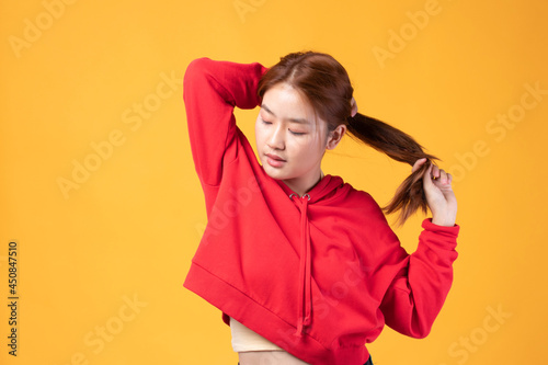 Portrait of beautiful young Asian girl model long hair in red coat summer clothes feeling smile, happy and enjoying in studio isolated on yellow background.
