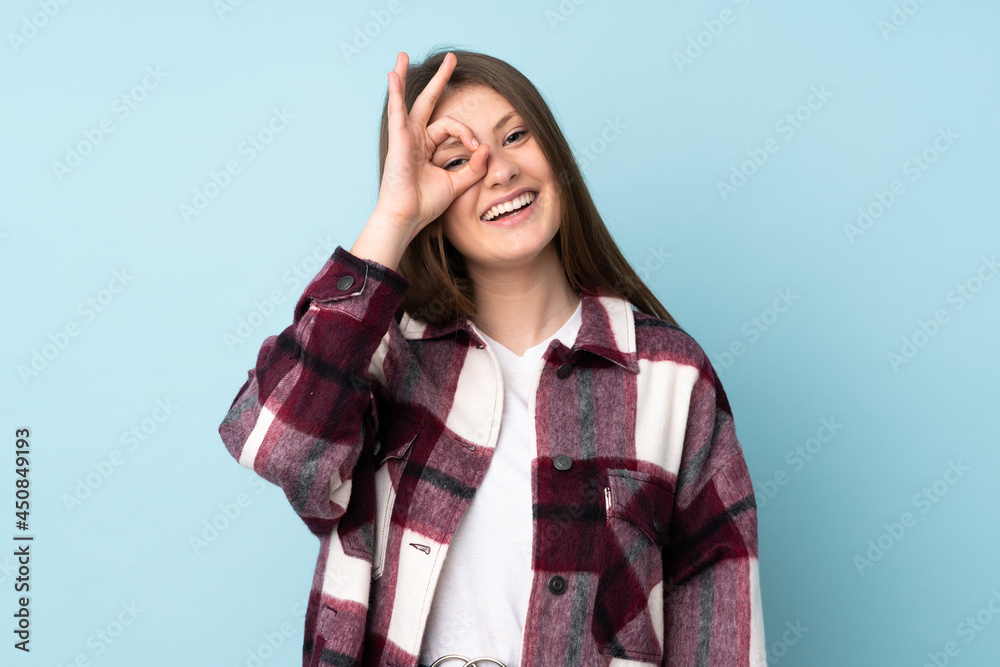 Teenager caucasian girl isolated on blue background showing ok sign with fingers Teenager caucasian girl isolated on blue background showing ok sign with fingers