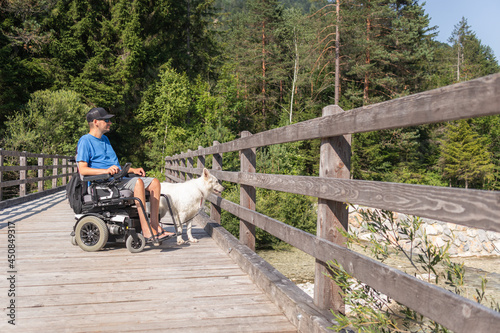 Disabled man on wheelchair with his dog on a trip in nature.