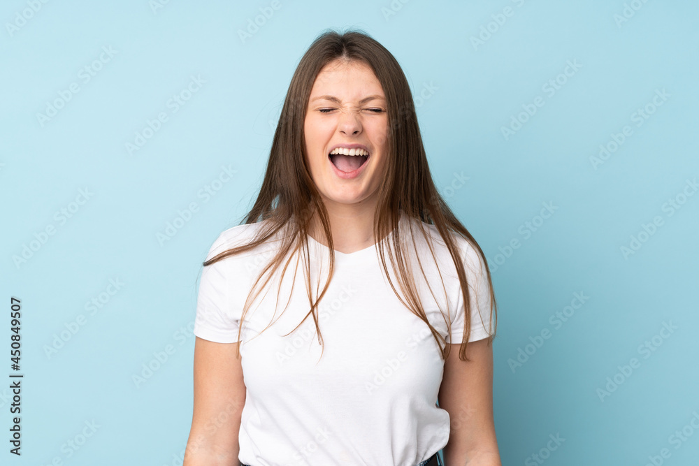 Teenager caucasian girl isolated on blue background shouting to the front with mouth wide open Teenager caucasian girl isolated on blue background shouting to the front with mouth wide open