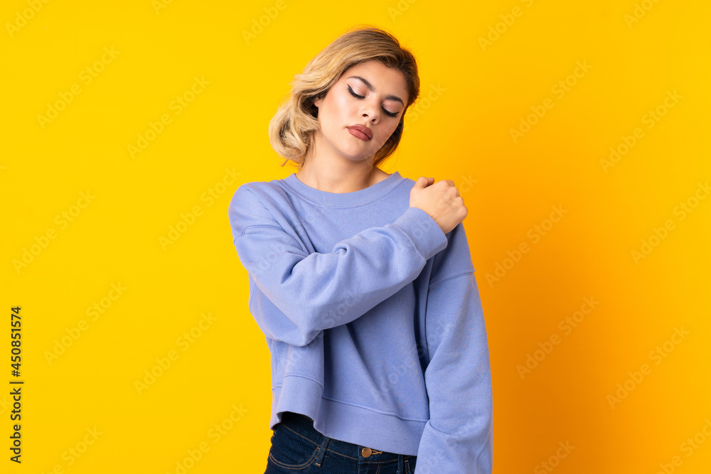 Young Russian woman isolated on yellow background suffering from pain in shoulder for having made an effort Young Russian woman isolated on yellow background suffering from pain in shoulder for having made an effort