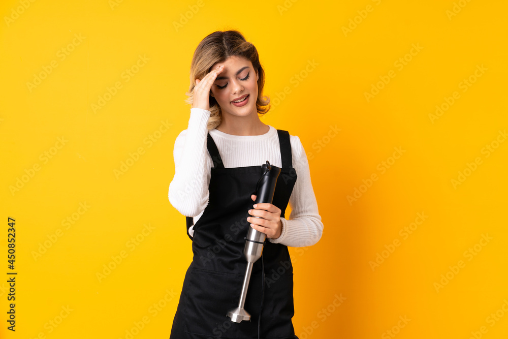 Girl using hand blender isolated on yellow background laughing Girl using hand blender isolated on yellow background laughing