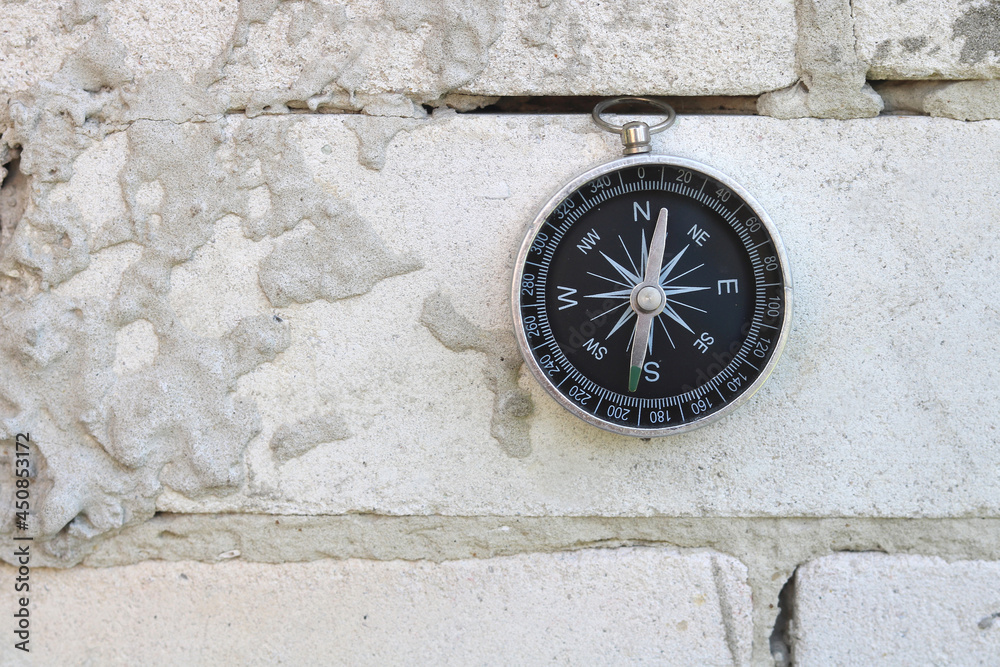 Classic navigation compass on brick wall background as symbol of tourism with compass, travel with compass and outdoor activities with compass Classic navigation compass on brick wall background as symbol of tourism with compass, travel with compass and outdoor activities with compass