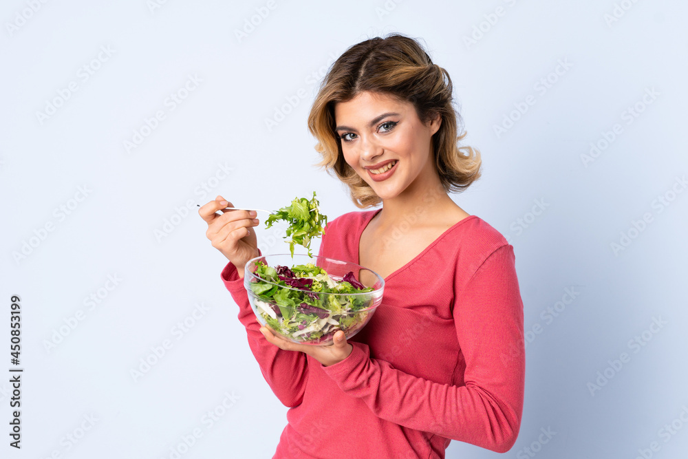 Teenager woman with salad isolated on blue background Teenager woman with salad isolated on blue background
