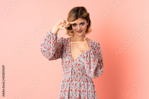 Young Russian woman isolated on pink background focusing face. Framing symbol © luismolinero