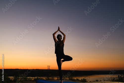 Female silhouette stand in tree yoga positon at sunrise horizon, find balance in healthy life
