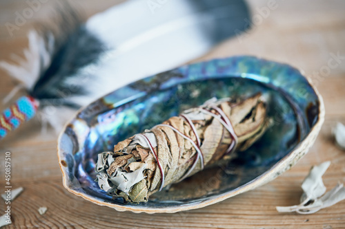 Spirituelle Raumreinigung - Smudge Stick (Kräuterbünder) Weißer Salbei und Yerba Santa wird in einer Abalone geräuchert photo