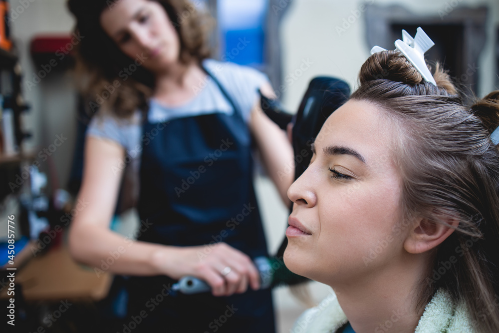 Side view of a woman customer getting a new hairstyle by female hairdresser. Side view of a woman customer getting a new hairstyle by female hairdresser.
