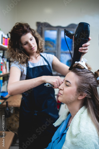 Side view of a woman customer getting a new hairstyle by female hairdresser.