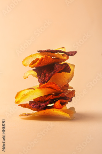 Stacked stack of organic vegetable chips on colored background photo