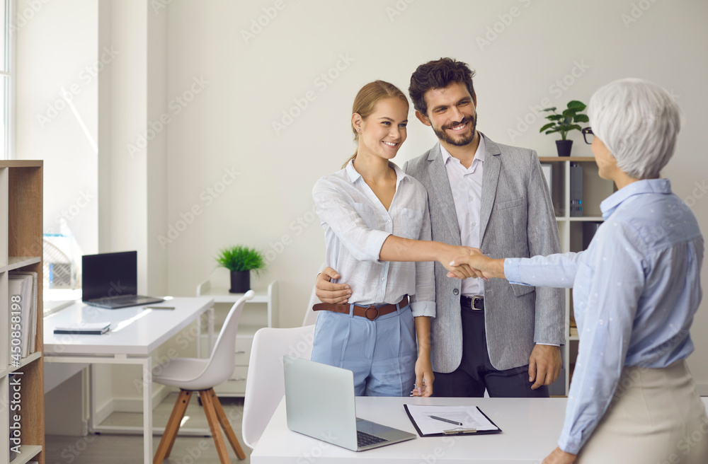 Clients shaking hands with bank manager. Couple of future house buyers exchanging handshake with real estate agent. Happy family thanking loan advisor for consultation meeting. Copy space background Clients shaking hands with bank manager. Couple of future house buyers exchanging handshake with real estate agent. Happy family thanking loan advisor for consultation meeting. Copy space background