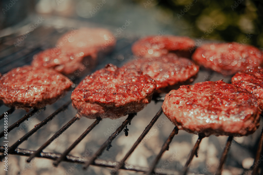 Detail of fresh and natural hamburgers cooking on the grill during an outdoor barbecue